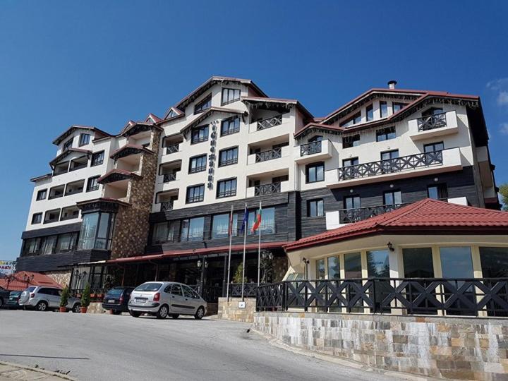 un gran edificio con coches estacionados frente a él en Snezhanka Apartments TMF, en Pamporovo