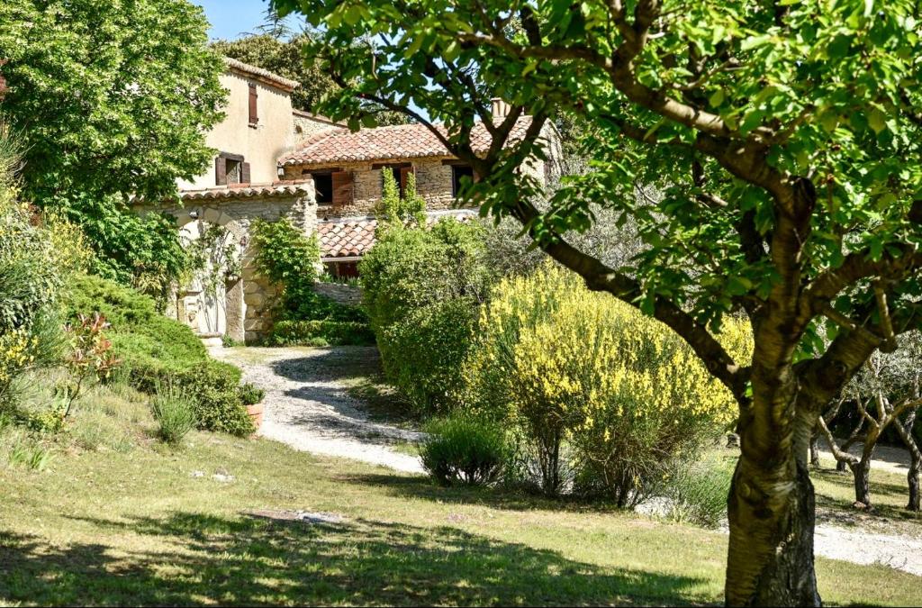 une maison dans un jardin avec un arbre au premier plan dans l'établissement B&B le boissol, à Entrechaux