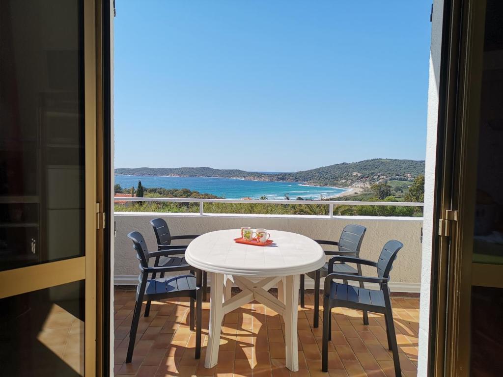 stół i krzesła na balkonie z widokiem na ocean w obiekcie Colocha w mieście Cargèse