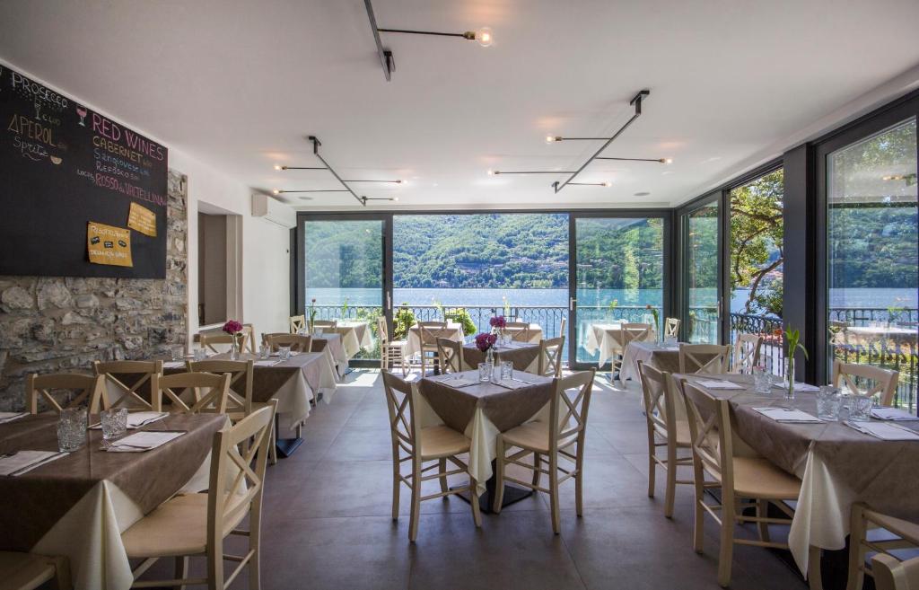 a restaurant with tables and chairs and large windows at Hotel Orso Bruno in Carate Urio