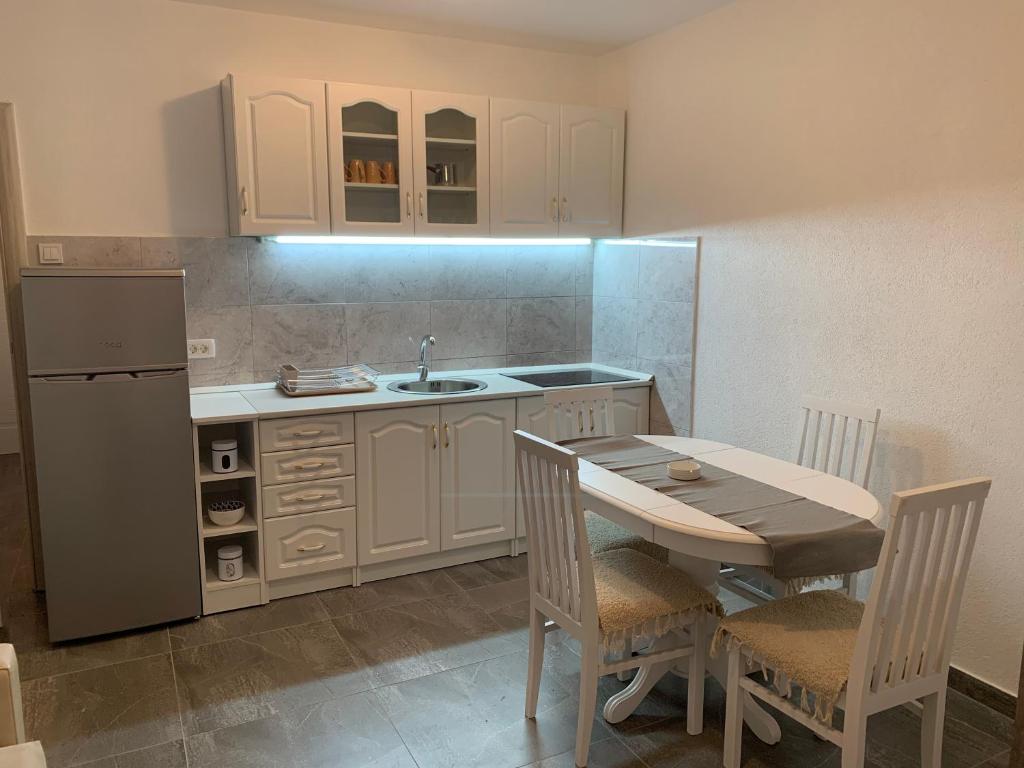 La cuisine est équipée d'une table, d'un évier et d'un réfrigérateur. dans l'établissement Apartment Rena, à Budva
