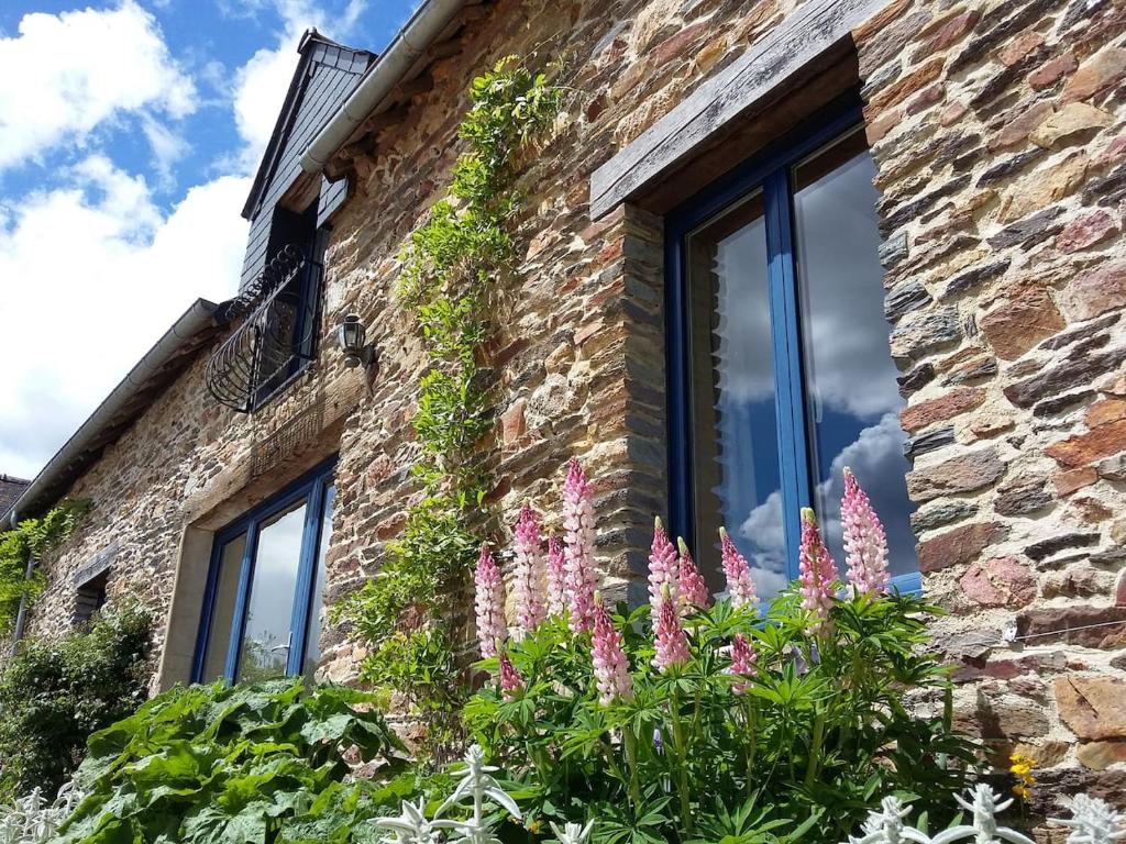 un edificio de ladrillo con ventanas y flores rosas en Le Grenier, La Vieille Ferme, en Ruffiac