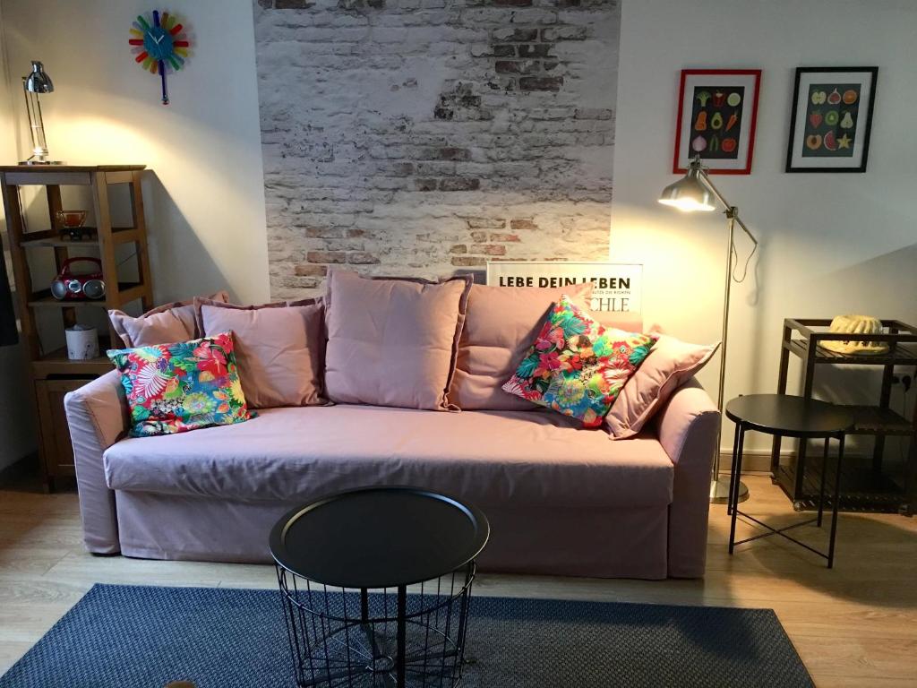 ein Wohnzimmer mit einer rosa Couch mit Kissen in der Unterkunft l’Atelier in Sélestat