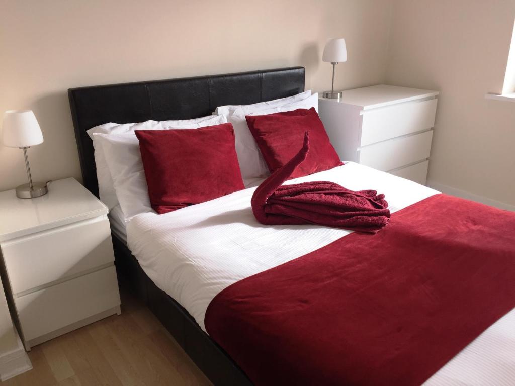 a bedroom with a large bed with red pillows at Contemporary Apartments, Balcony & Parking in Basingstoke
