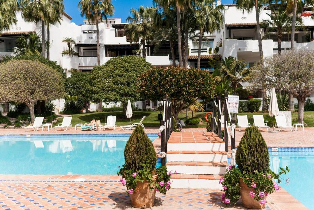 una piscina con un hotel sullo sfondo di Marina Puente Romano - Groundfloor - 3 Bedrooms a Marbella