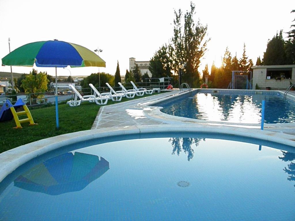 a large swimming pool with an umbrella and chairs at Hotel El Prado by Vivere Stays in Carrascosa del Campo
