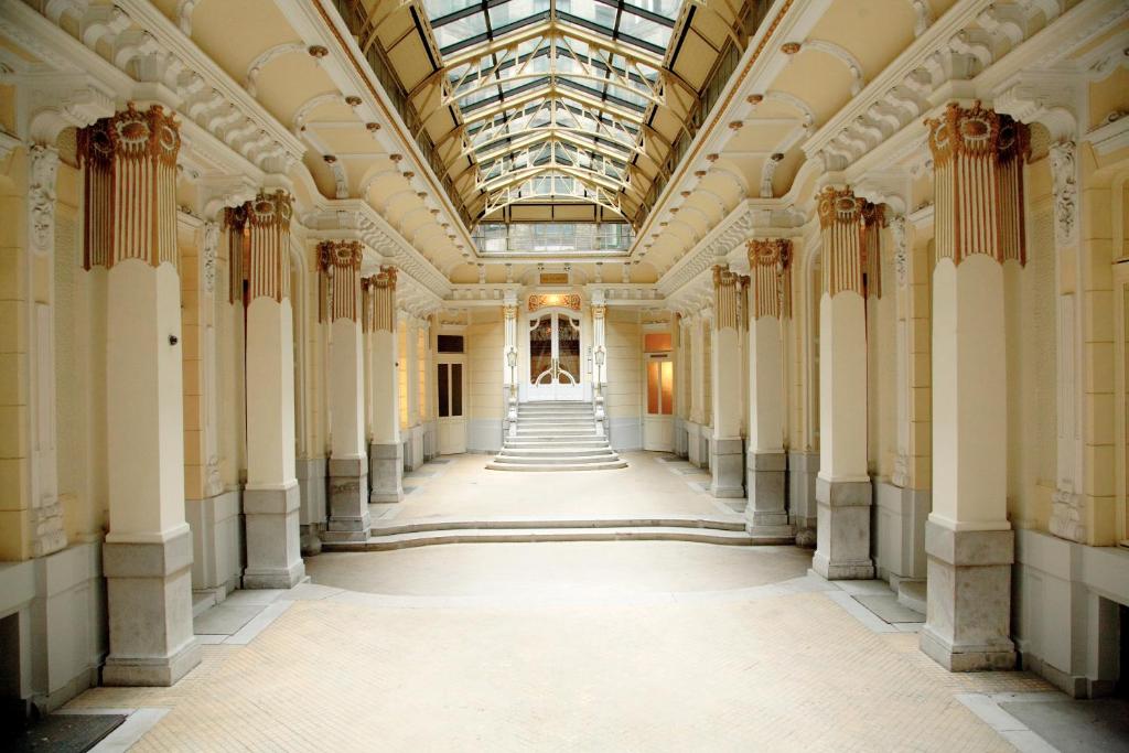 un corridoio vuoto in un edificio con colonne e soffitto di vetro di Maverick Hostel & Ensuites a Budapest