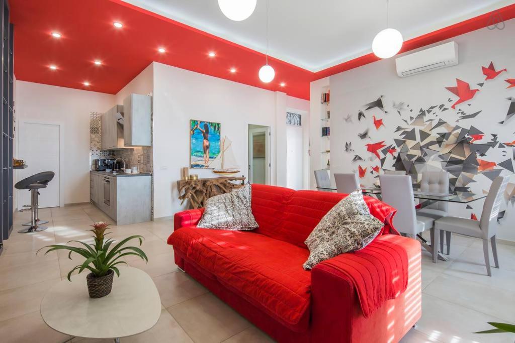 a red couch in a living room with a table at Sara’s SeaView Apartment in Salerno