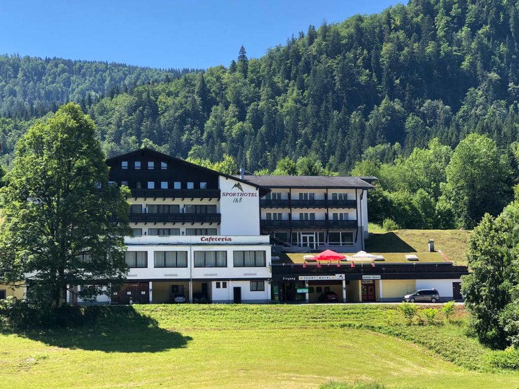 un gran edificio con una montaña en el fondo en Sporthotel am Ötscher, en Lackenhof