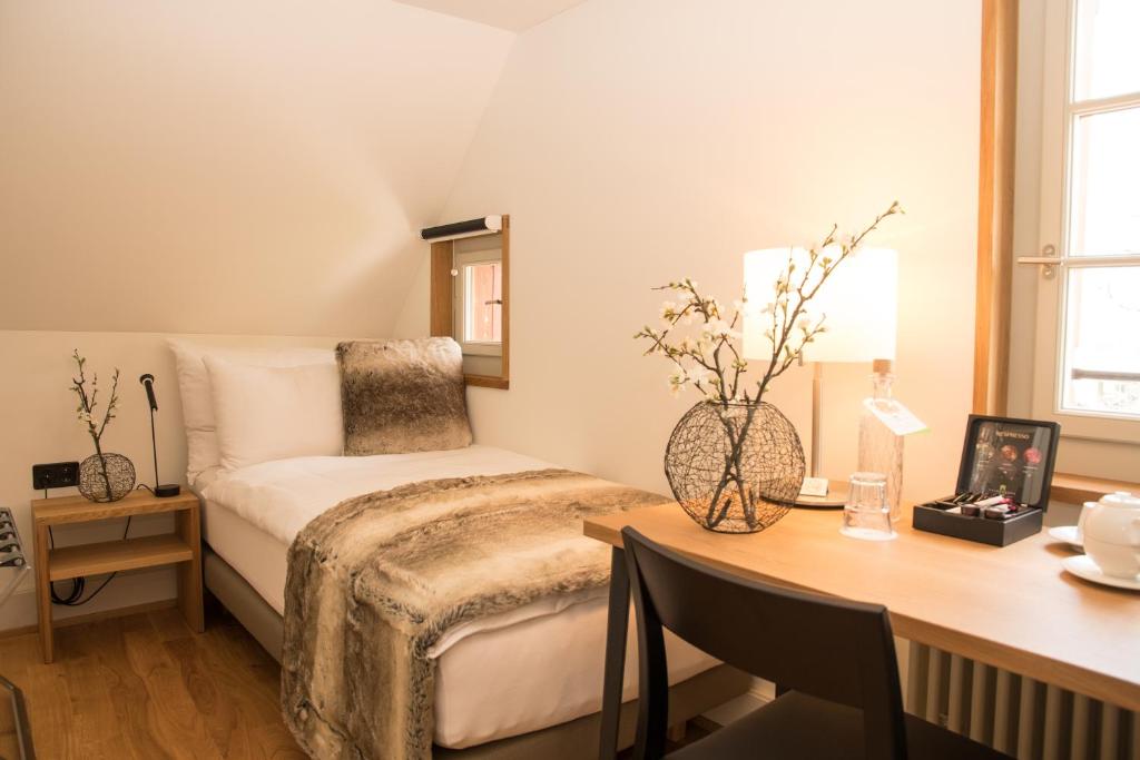 a bedroom with a bed and a desk with a desk at Hotel Restaurant Falkenburg in St. Gallen