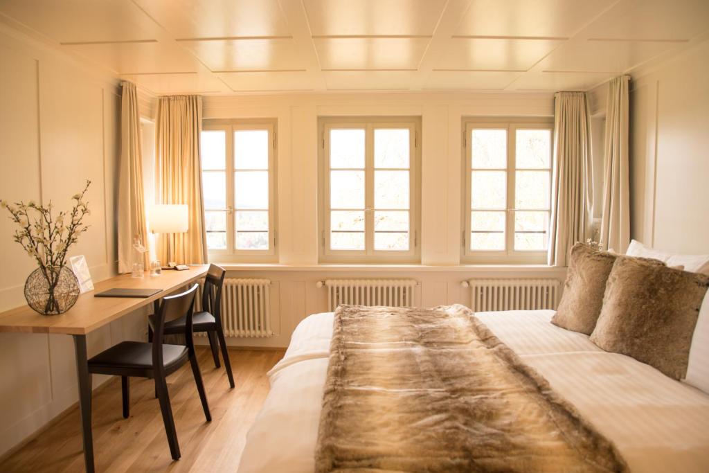 a bedroom with a bed and a desk and windows at Hotel Restaurant Falkenburg in St. Gallen