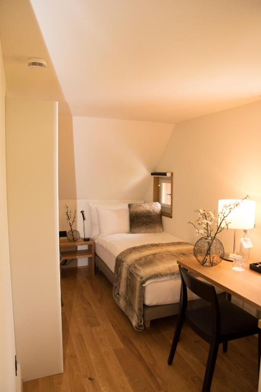 a bedroom with a bed and a desk and a table at Hotel Restaurant Falkenburg in St. Gallen