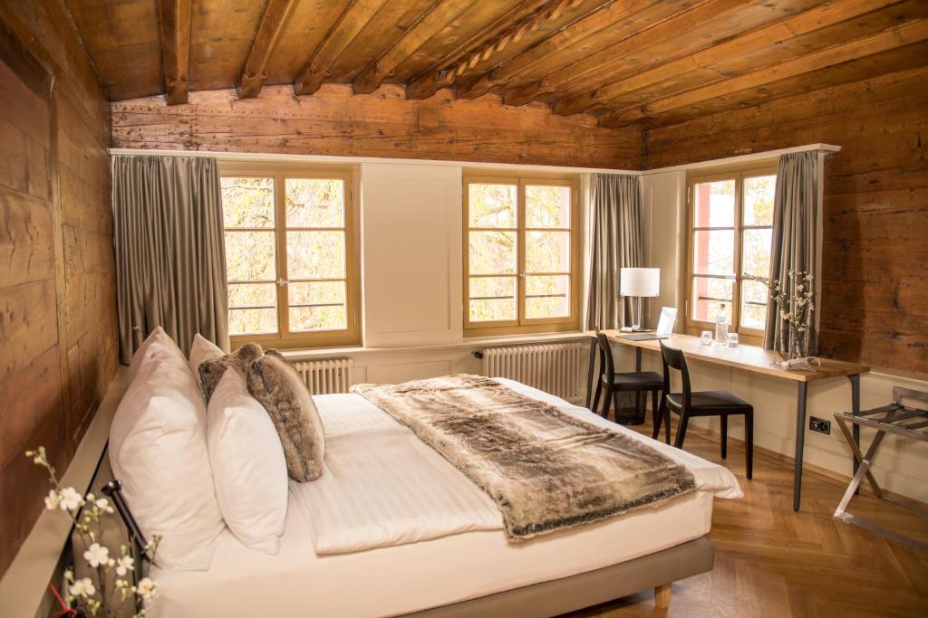 a bedroom with a bed and a desk and windows at Hotel Restaurant Falkenburg in St. Gallen