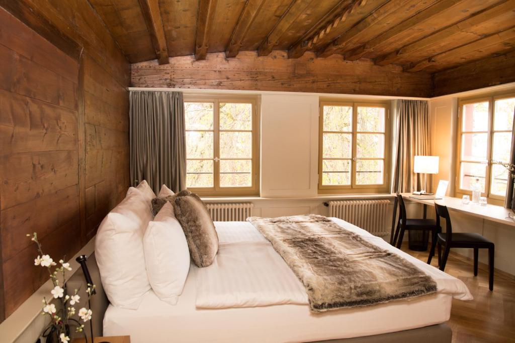 a bedroom with a bed and a desk and windows at Hotel Restaurant Falkenburg in St. Gallen