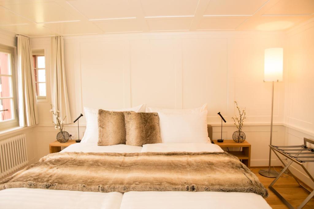 a white bedroom with a large bed with pillows at Hotel Restaurant Falkenburg in St. Gallen