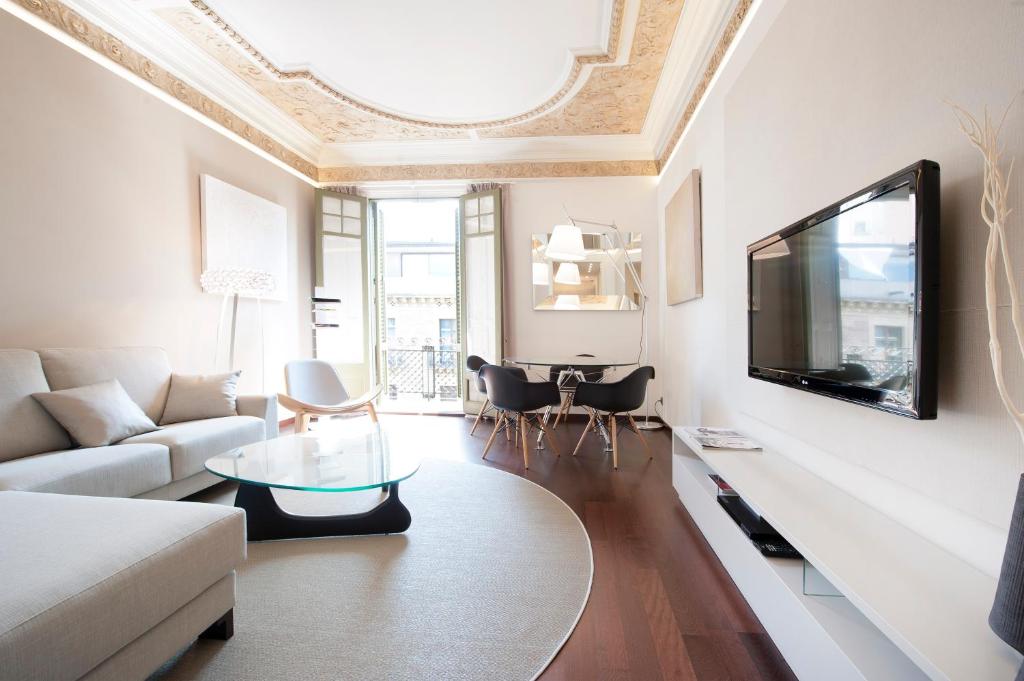 sala de estar con sofá y TV en la pared en You Stylish El Born Apartments, en Barcelona