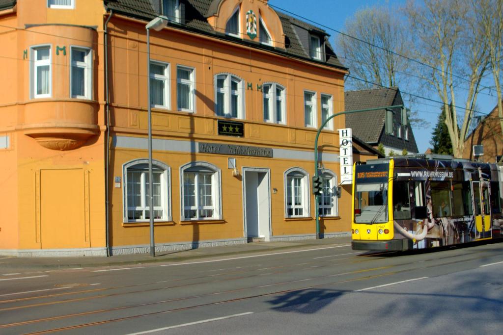 Ein gelber Bus fährt eine Straße entlang neben einem Gebäude in der Unterkunft Hotel Wilhelmshöhe in Essen