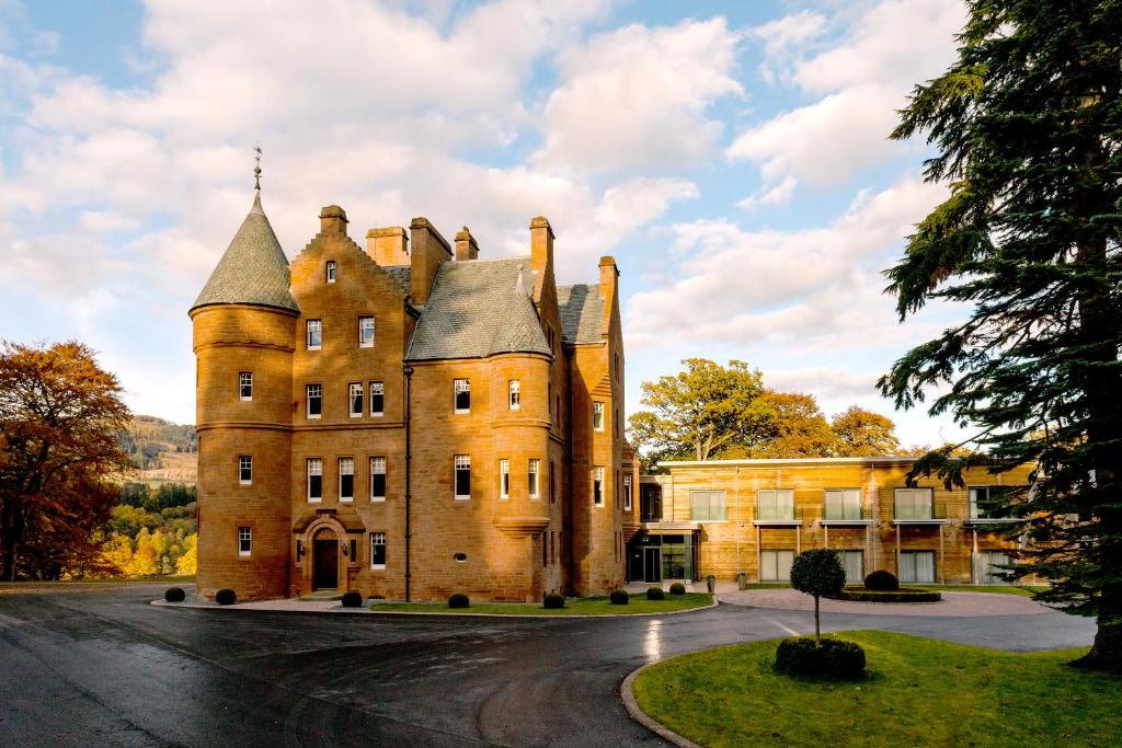 un antiguo castillo en una carretera frente a un edificio en Fonab Castle Hotel, en Pitlochry