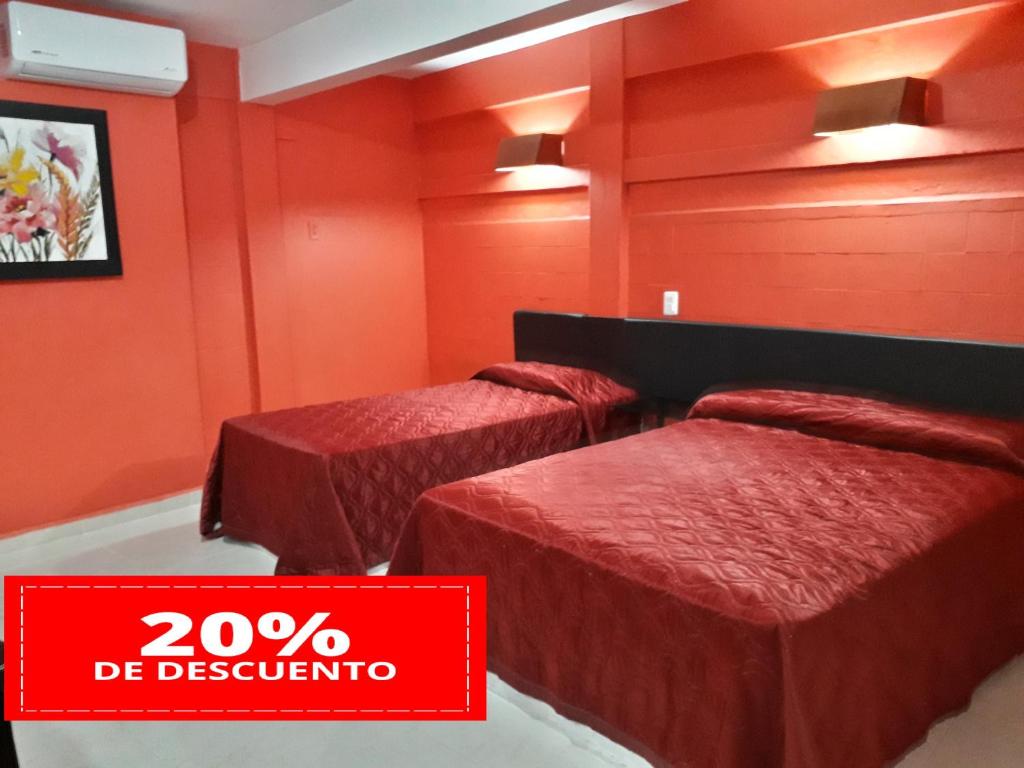 a red room with two beds and a sign that says de descriptor at Hotel Michelle in San Andrés Tuxtla