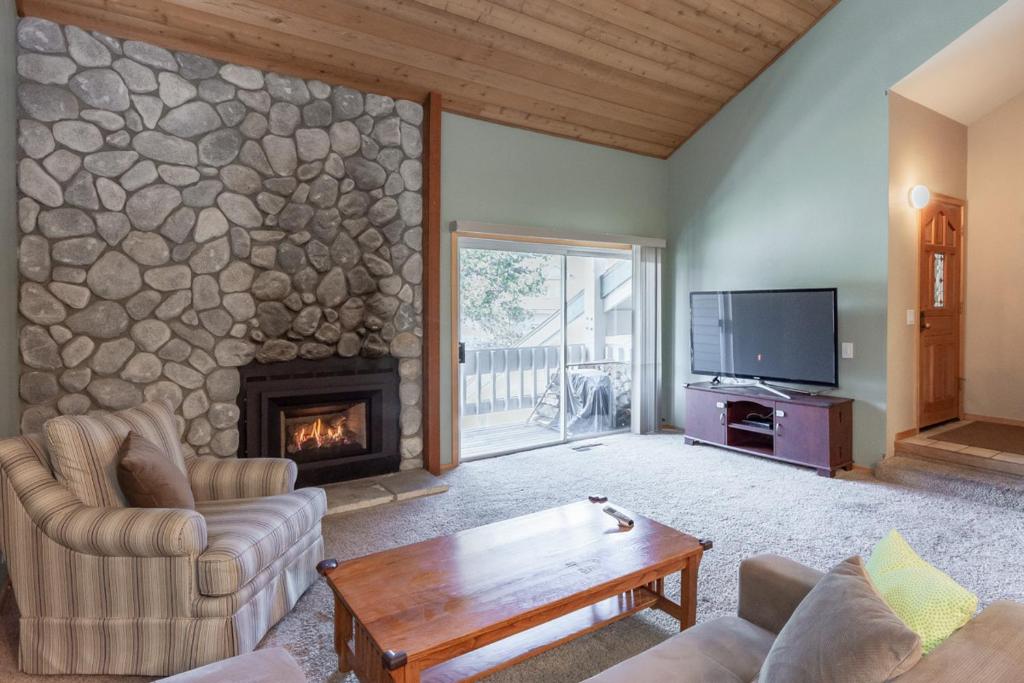 a living room with a stone wall with a fireplace at Snowcreek IV 588 in Mammoth Lakes