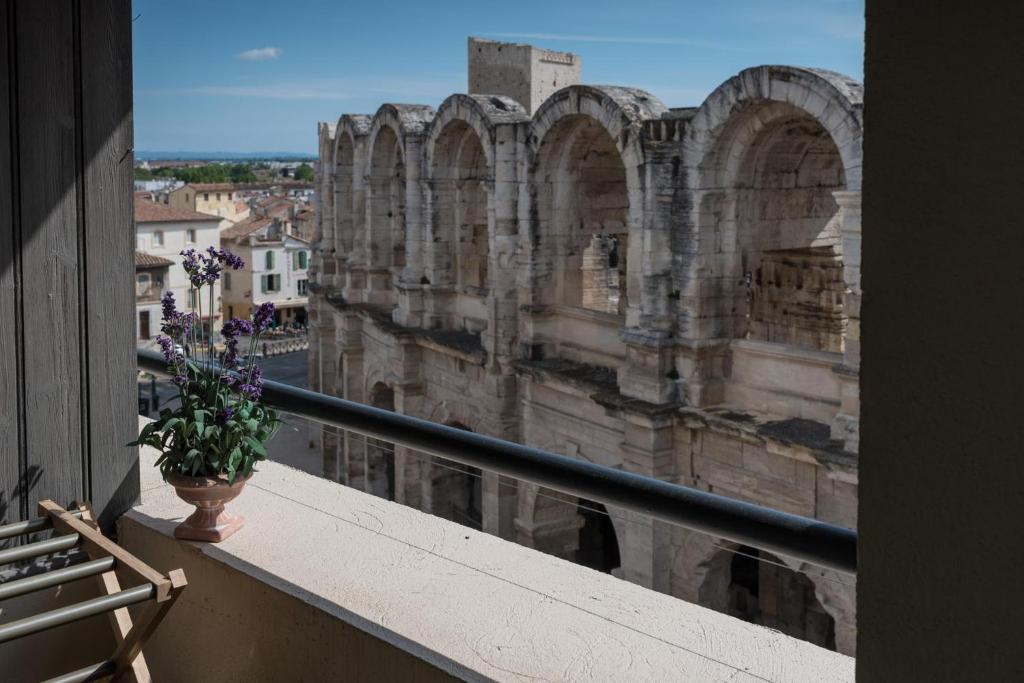 un vase de fleurs assis sur un balcon d'un bâtiment dans l'établissement Studio avec balcon donnant sur les Arènes d’Arles, à Arles