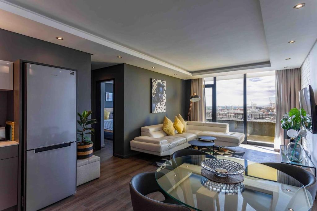 a living room with a couch and a table at Brand new penthouse with waterfront views in Cape Town