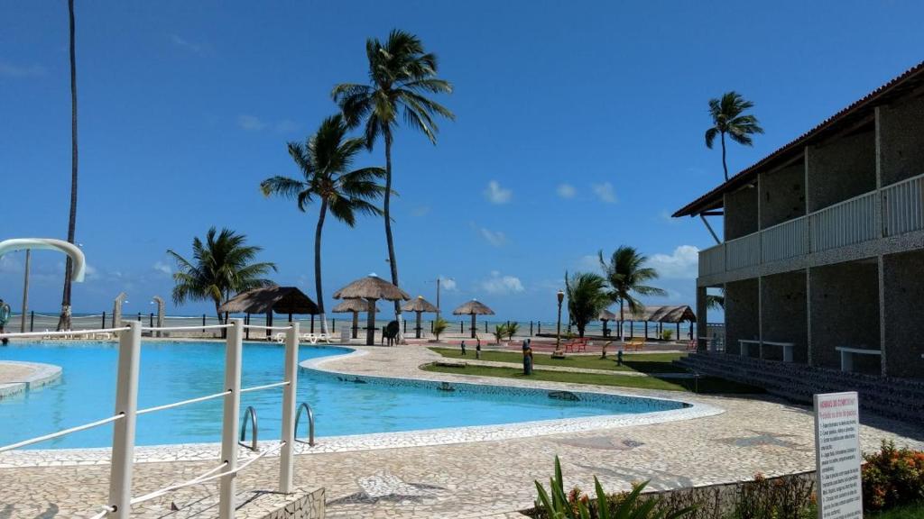 a resort with a swimming pool and palm trees at Village Galés Maragogi in Maragogi
