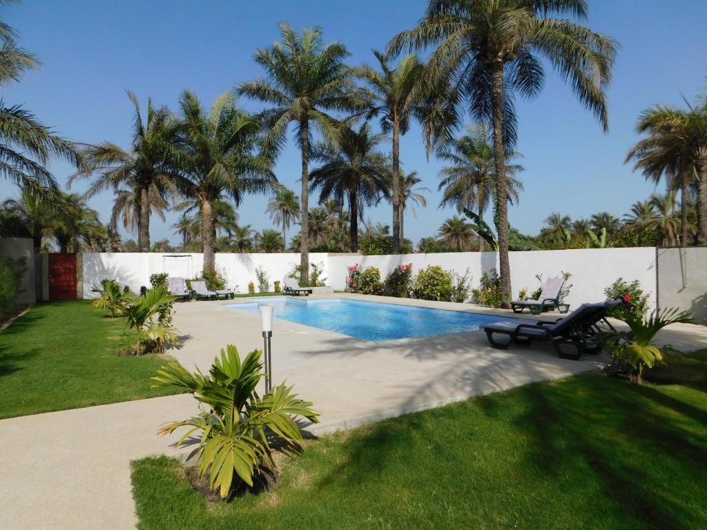 a swimming pool in a yard with palm trees at CAP BAY in Cap Skirring