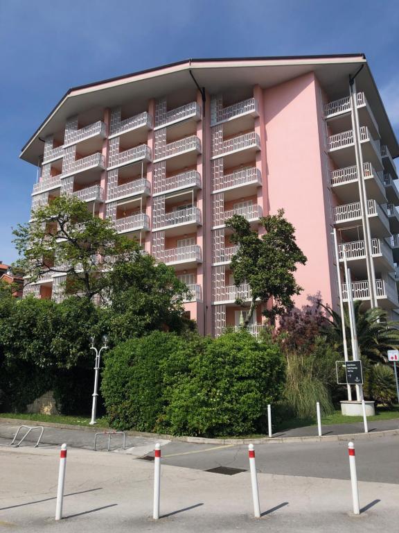 un edificio rosa con un estacionamiento delante de él en Room 211 - Aparthotel Jadranka, en Portorož