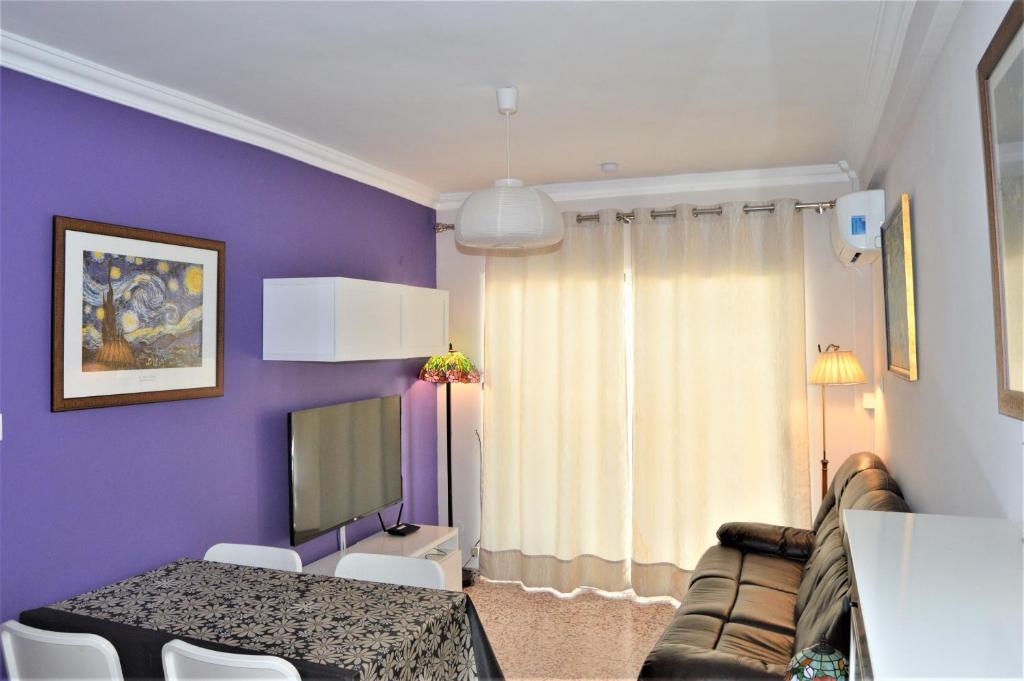 sala de estar con paredes de color púrpura, mesa y sofá en Casa Rocío en Nerja, en Nerja