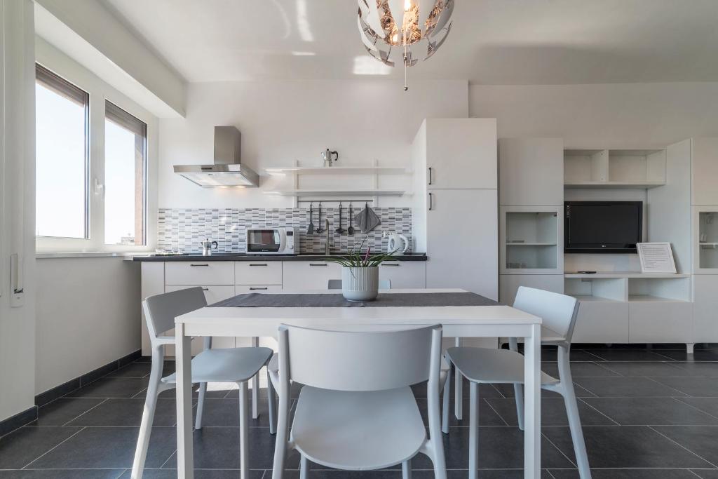 a white kitchen with a white table and chairs at Nomentana White Apartments in Rome