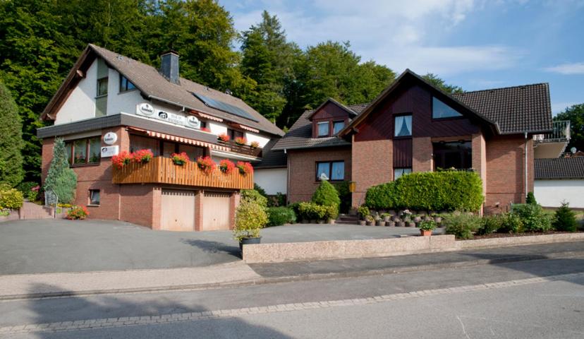 een groot huis met bloemen op een oprit bij Pension Haus am Waldesrand in Schieder-Schwalenberg