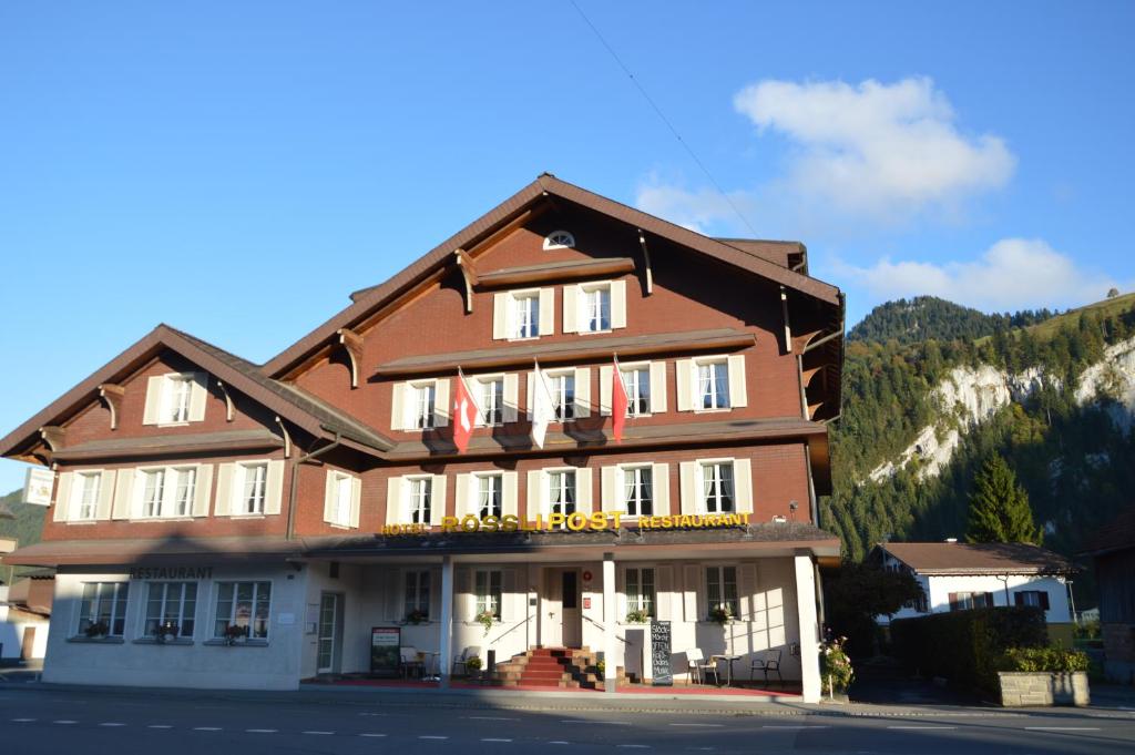 ein großes Gebäude mit Flaggen davor in der Unterkunft Hotel Garni Rösslipost in Unteriberg