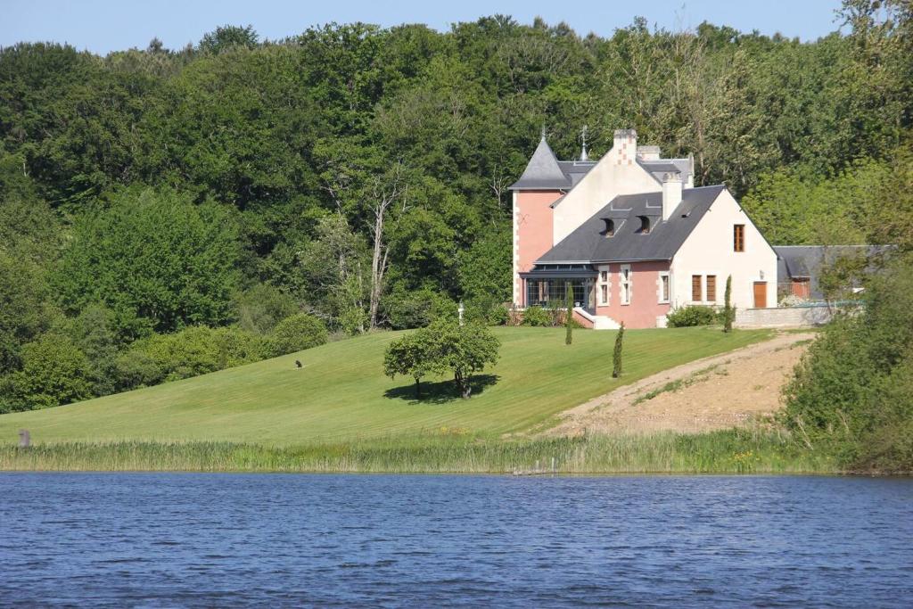 a large house on a hill next to a body of water at Chateau de Vau Rozet in Continvoir