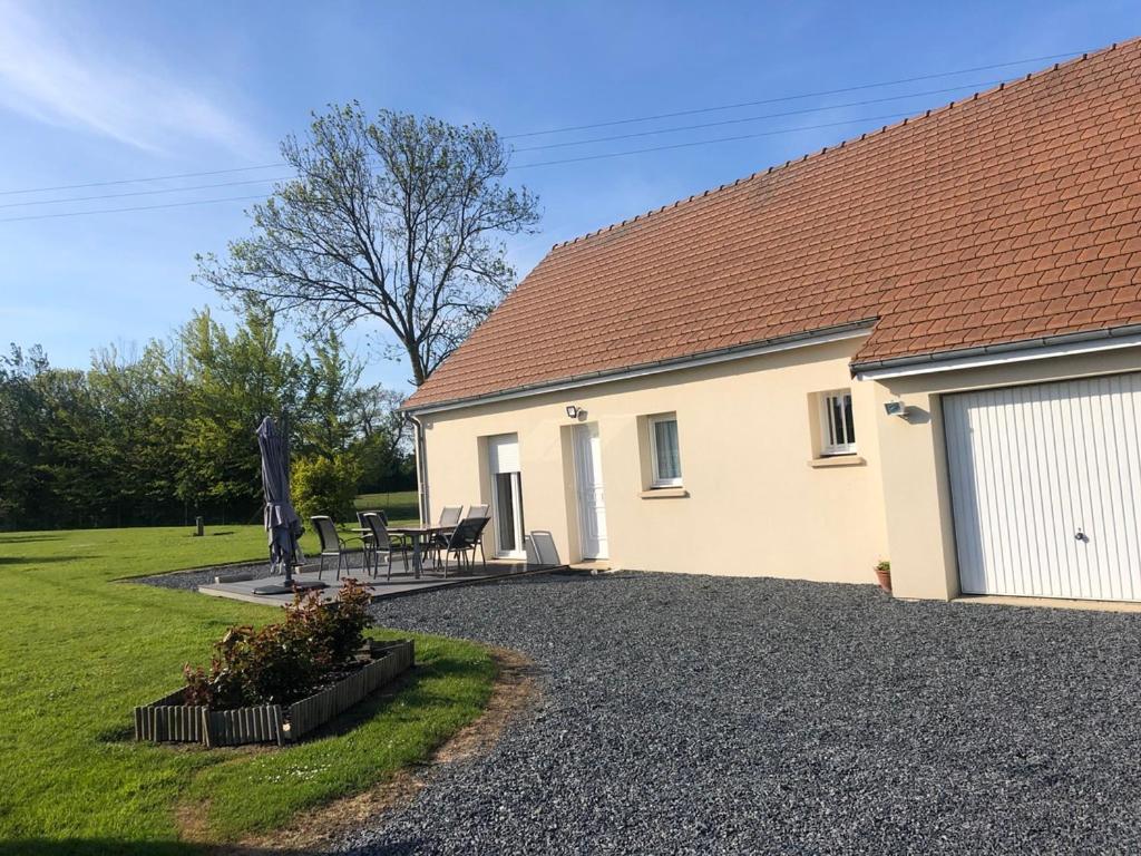 a house with a table and chairs in front of it at pavillon individuel in Cricqueville-en-Bessin