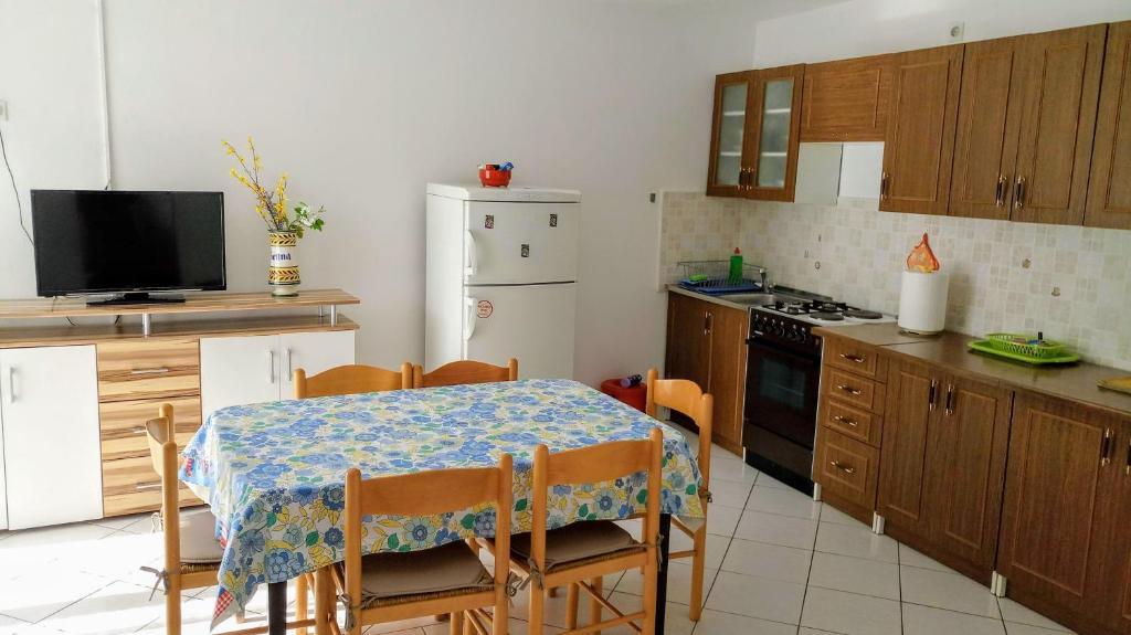 eine Küche mit einem Tisch und Stühlen sowie eine Küche mit einem Herd in der Unterkunft Apartments Tatjana in Martinšćica