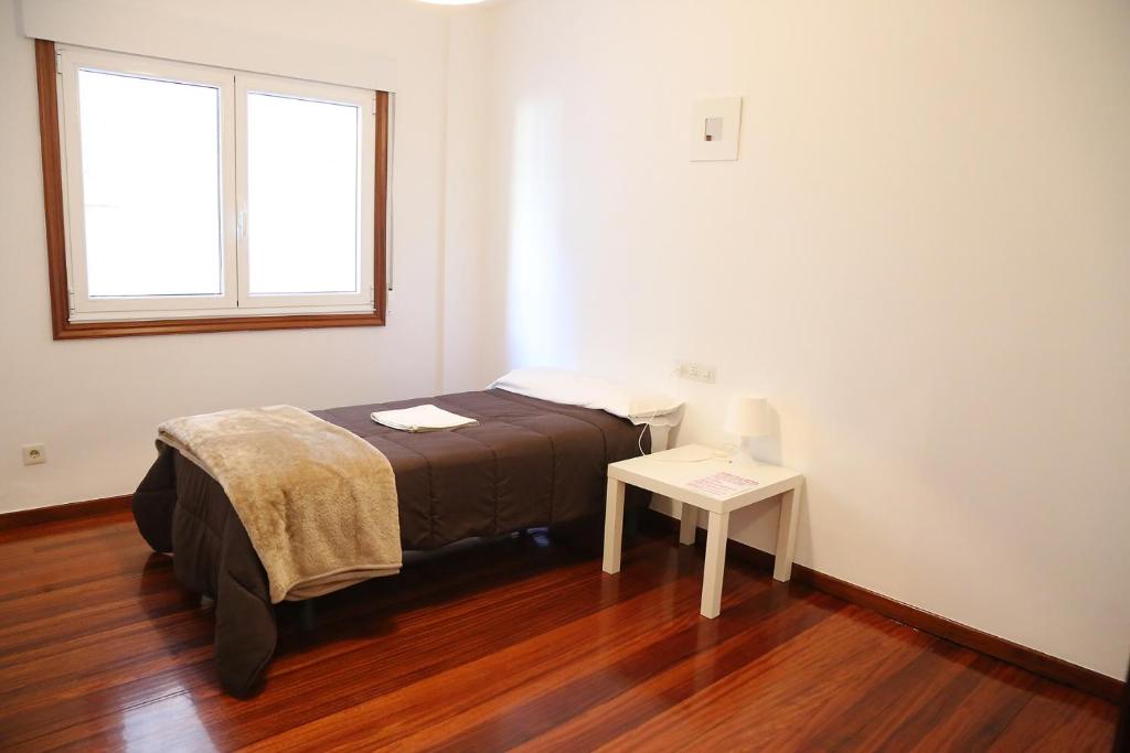 Dormitorio pequeño con cama y mesa en PENSION DE PEREGRINOS LA MODERNA, en Caldas de Reis