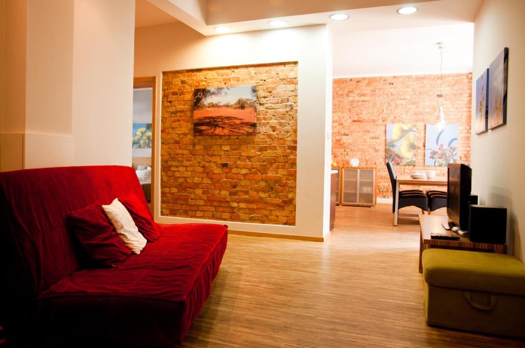 a living room with a red couch and a brick wall at Apartamenty 23 in Poznań