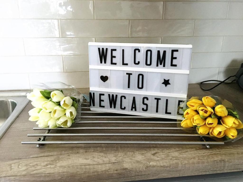 una bienvenida al cartel de Newcastle en un mostrador con tulipanes en Patio Bliss! en Newcastle