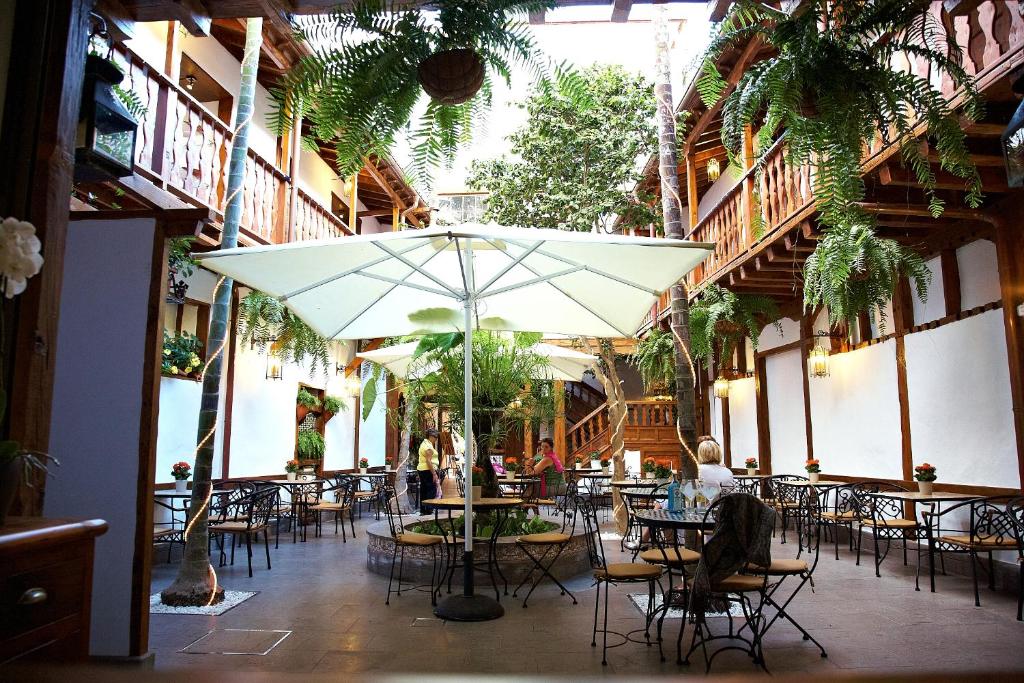 un patio con mesas, sillas y una sombrilla en Hotel Emblemático San Agustin, en Icod de los Vinos