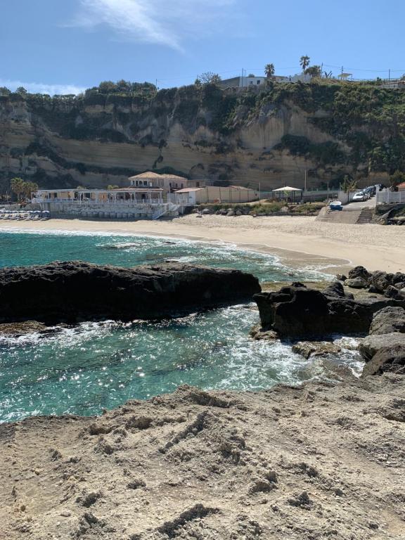 a beach with rocks and the ocean and a building at B&B A casa di Picci in Santa Domenica