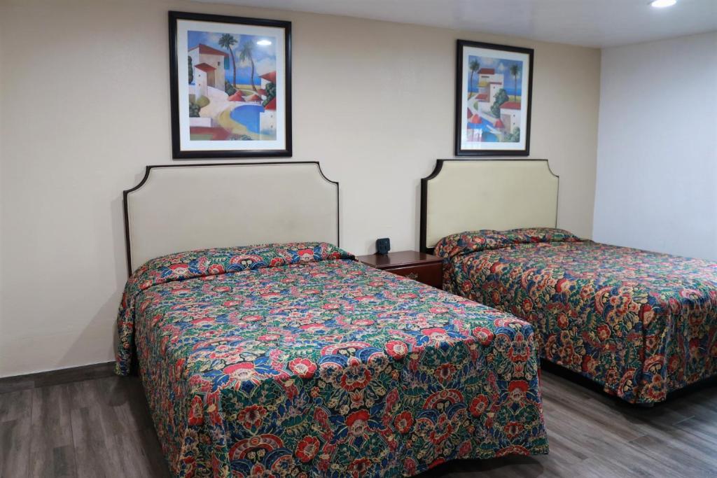 2 Betten in einem Zimmer mit Gemälden an der Wand in der Unterkunft Welcome Inn Motel in Montclair
