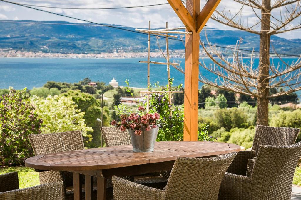 einen Holztisch mit Stühlen und eine Vase aus Blumen in der Unterkunft Panorama Fanari studios and apartments in Argostoli