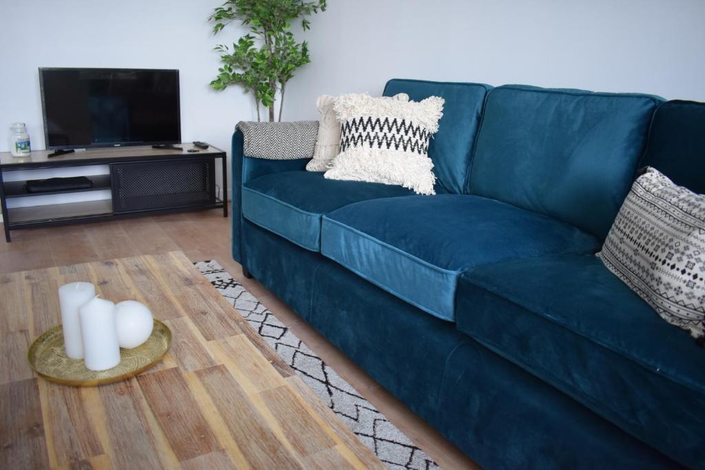 ein blaues Sofa im Wohnzimmer mit einem Tisch in der Unterkunft Le Petit Saint Ouennais à 30min de Paris in Saint-Ouen-lʼAumône