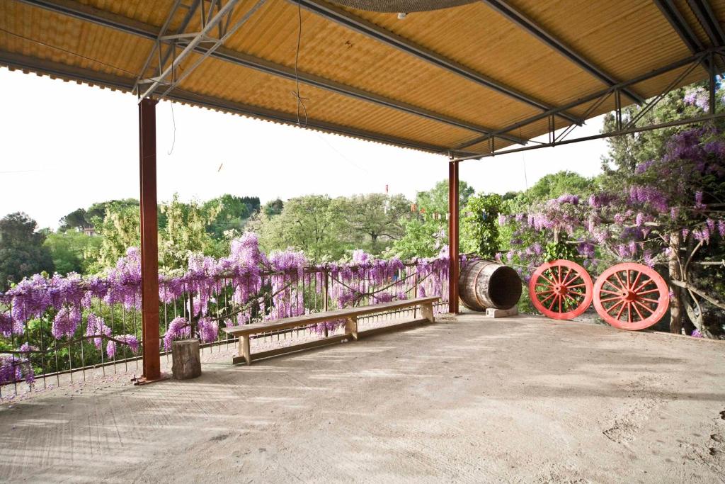 a pavilion with purple flowers and red wagon wheels at Agriturismo Cognanello in Montepulciano