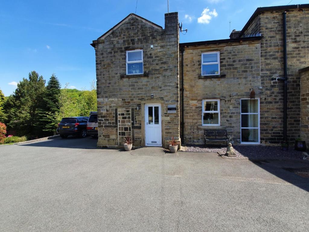 ein Backsteinhaus mit einem davor geparkt in der Unterkunft Hazeldene Cottage in Holmfirth