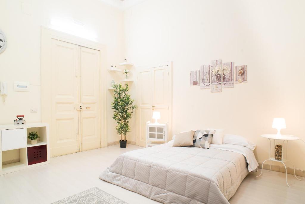 Casa Napoletana - Alighieri في نابولي: غرفة نوم بيضاء فيها سرير وزرع