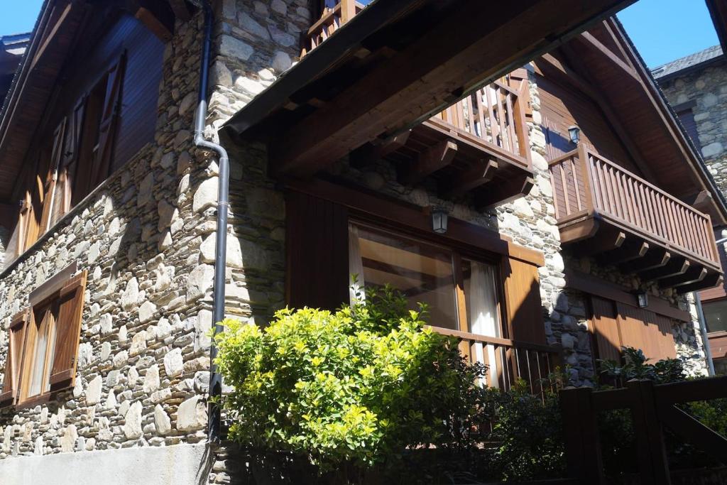 a building with a balcony and a bush in front of it at Acogedora casita en el Pallars in Isil