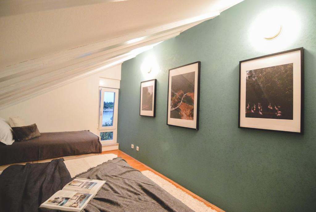 a bedroom with a green wall with pictures on it at Apartments Lucija in Zadar