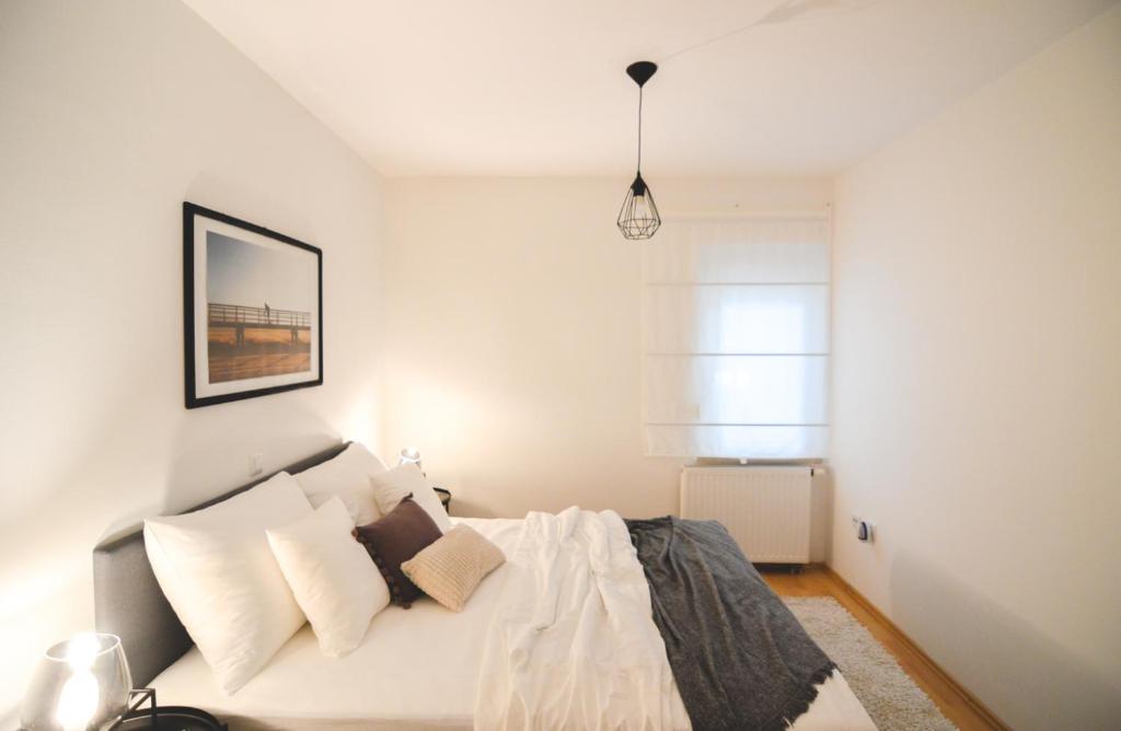 a bedroom with a bed with white sheets and pillows at Apartments Lucija in Zadar